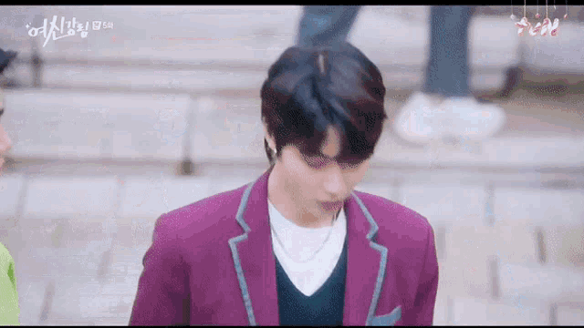 a man in a purple suit is standing on a sidewalk .