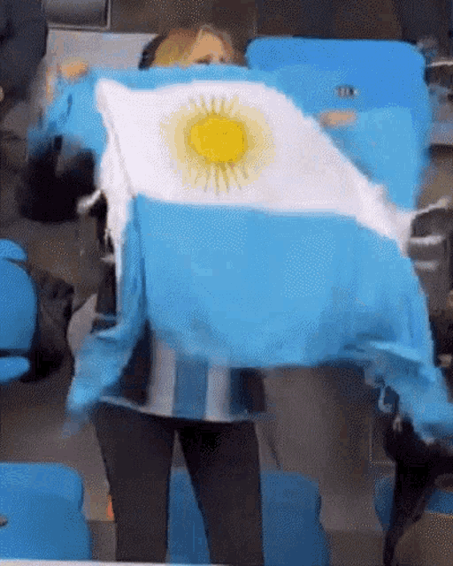 a woman is holding a blue and white flag with the sun on it