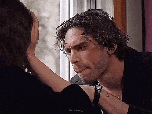 a man and a woman are touching each other 's foreheads while looking out a window .