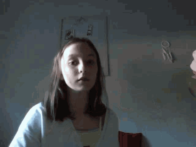 a young girl in a blue sweater is blowing a kiss