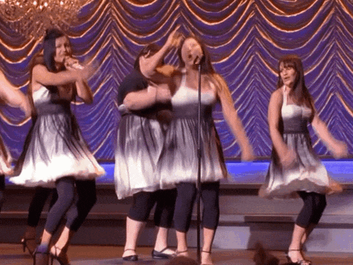 a group of women are singing and dancing on stage