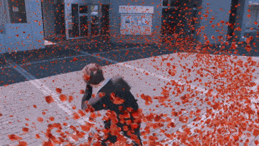 a person is surrounded by red petals on a brick pavement