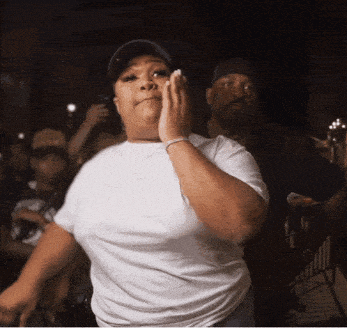 a woman in a white t-shirt is dancing in front of a crowd