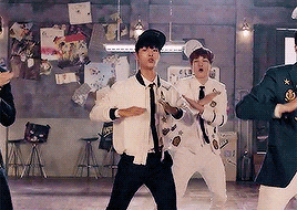 a group of young men are dancing in a room with a microphone .