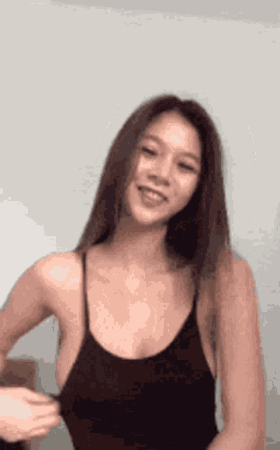 a woman wearing a black tank top is smiling and looking at the camera