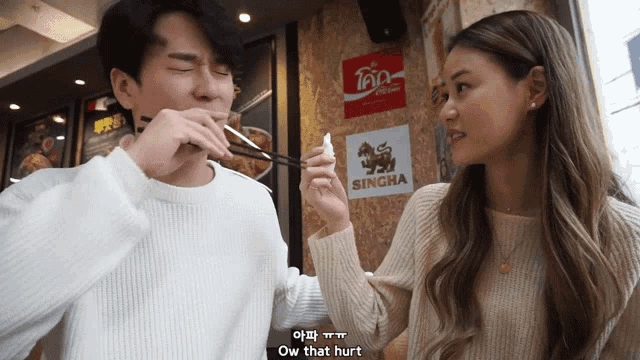 a man is eating something with chopsticks while a woman says ow that hurt