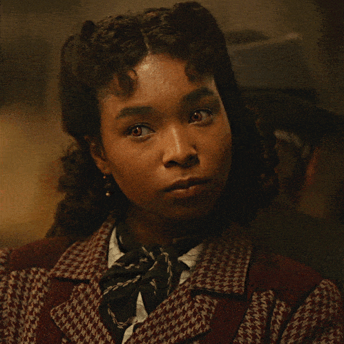 a close up of a woman 's face wearing a plaid jacket