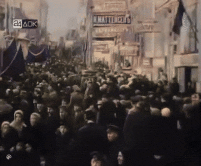 a crowd of people walking down a street with a sign that says ' n. mattel ' on it