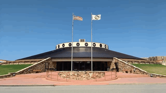 two flags are flying in front of a building with circles on it