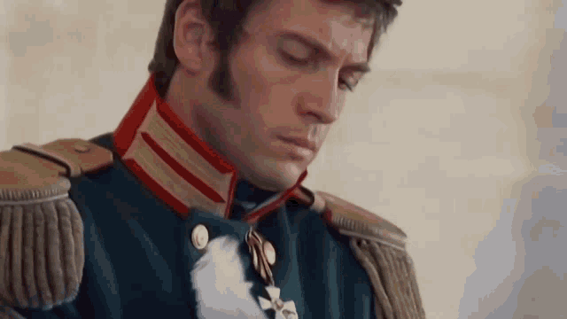 a man in a military uniform is looking down with his eyes closed