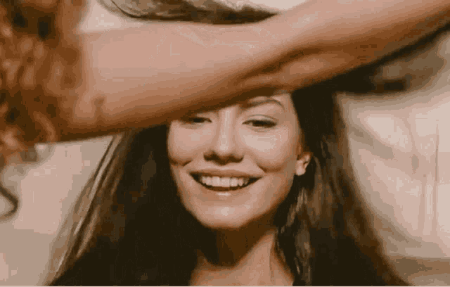 a woman with long hair is smiling while another woman holds her hair over her head .