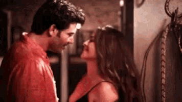 a man and a woman are kissing in a room in front of a snake .