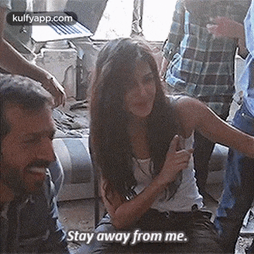 a woman is sitting in a room with a group of people and a man is talking to her .