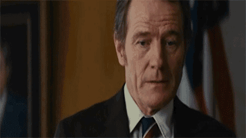 a man in a suit and tie says " by war " in front of an american flag