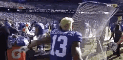 a football player wearing a number 13 jersey is standing in front of a net .