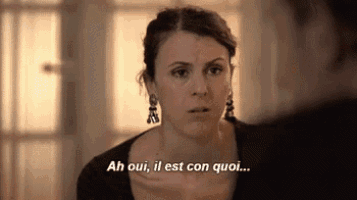 a woman is talking to a man in french while wearing earrings and a black shirt .