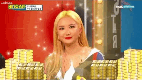a woman with blonde hair is sitting in front of a pile of gold coins .