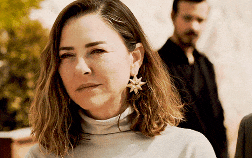 a woman wearing a turtleneck sweater and earrings with a star on them