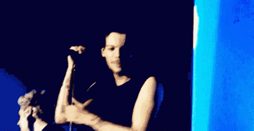 a man in a black tank top is holding a microphone