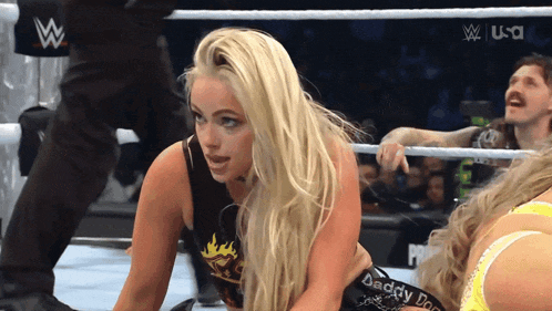 a woman in a wrestling ring is wearing a black top that says " daddy dom "