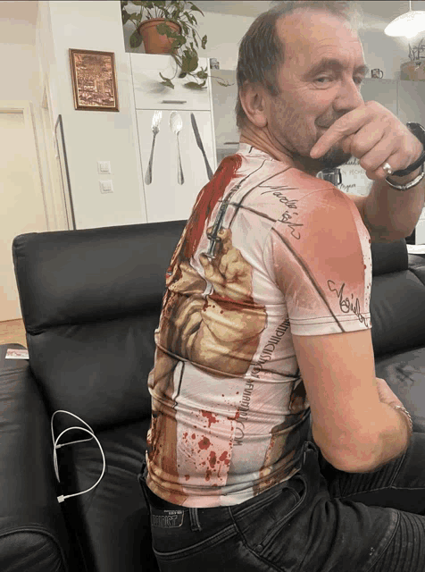 a man sitting on a couch wearing a t-shirt that says ' noise ' on the back