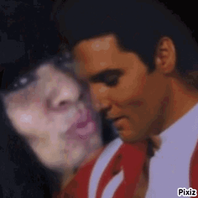 a man and a woman are kissing each other . the woman is wearing red lipstick .