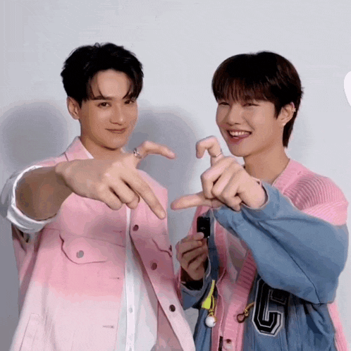 two boys are making a heart shape with their hands