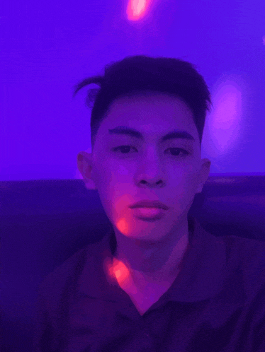 a young man is taking a selfie in front of a purple background