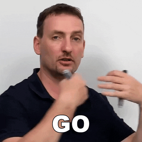 a man in a black shirt is holding a microphone and says go