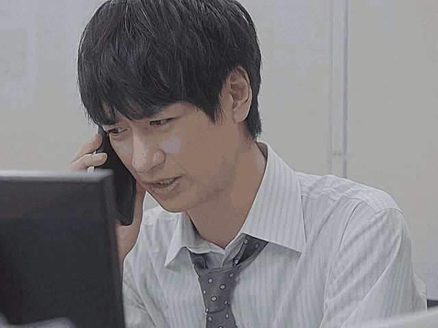 a man talking on a cell phone while looking at a computer screen