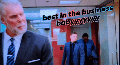 a man in a suit and tie stands in front of a sign that says best in the business baby
