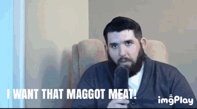 a man with a beard is sitting in a chair with the words " i want that maggot meat " below him