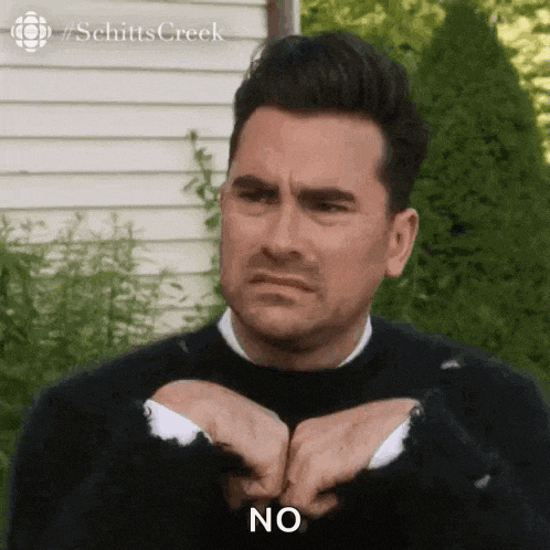 a man in a black sweater is making a funny face and holding his hands together .