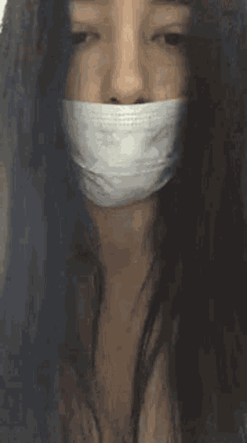 a woman with a white bandage on her mouth is looking at the camera .