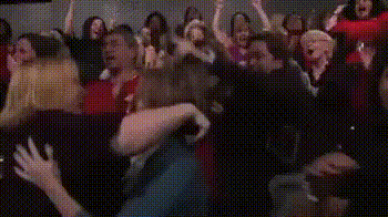 a crowd of people are sitting in a theater watching a movie and a woman is crying .