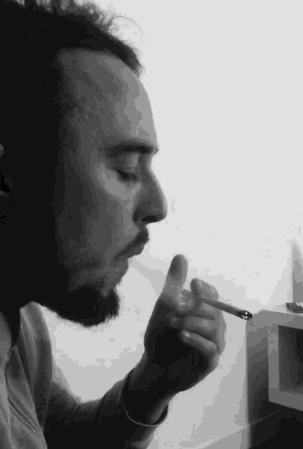 a man with a beard smoking a cigarette in a black and white photo