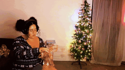a woman is sitting in front of a christmas tree