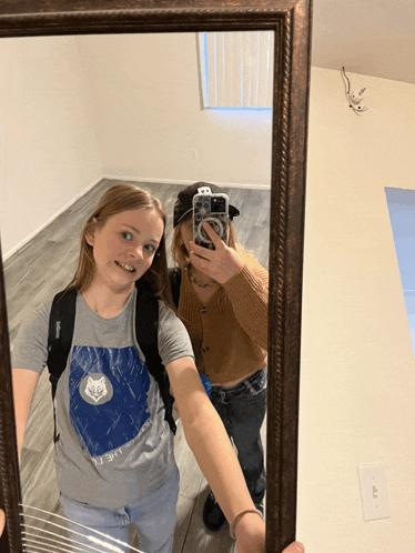 two girls are taking a picture of themselves in a mirror with one wearing a shirt that says life is a journey