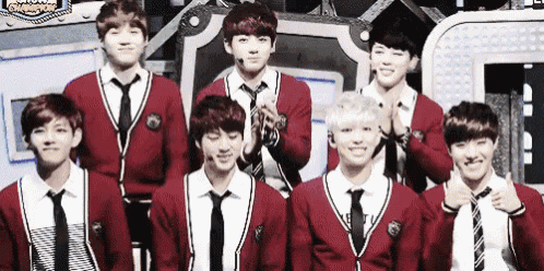 a group of young men wearing school uniforms and ties are standing next to each other on a stage .