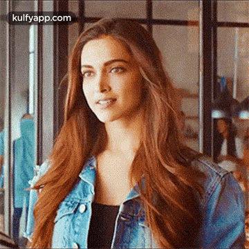 a woman with long red hair is wearing a denim jacket and a black tank top .