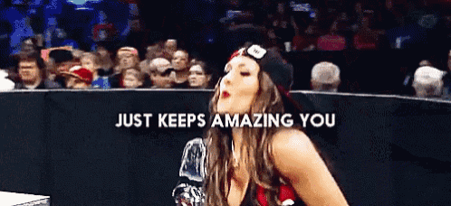 a female wrestler is standing in front of a crowd with the words just keeps amazing you above her