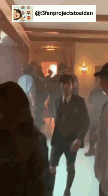 a man in a suit and tie is dancing in a hallway with a sticker that says t3fanprojecttoaidan