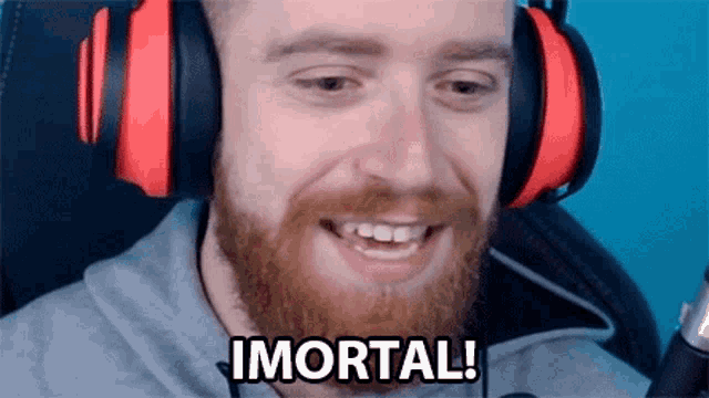a man with a beard wearing headphones is smiling and says immortal .