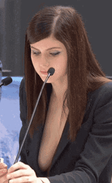 a woman with a plunging neckline speaking into a microphone