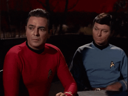 two men are sitting next to each other and one of them has a star trek patch on his chest