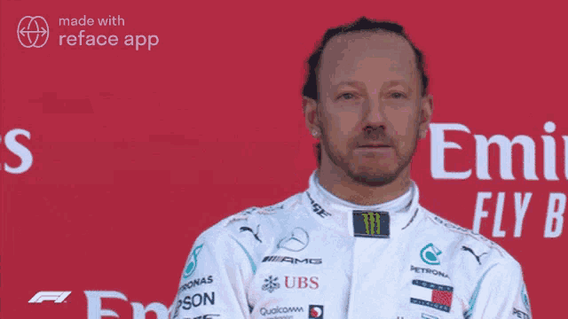 a man in a mercedes racing suit is standing in front of a emi fly b sign