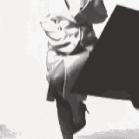 a black and white photo of a man in a suit holding a book .