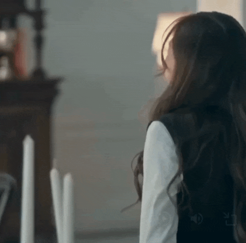 a woman with long hair is standing in front of a table with candles on it