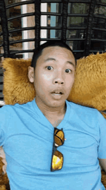 a man in a blue shirt and sunglasses is sitting in a chair