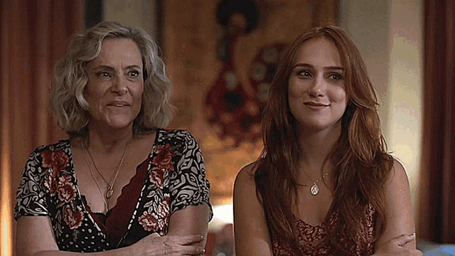 two women are sitting next to each other in a room